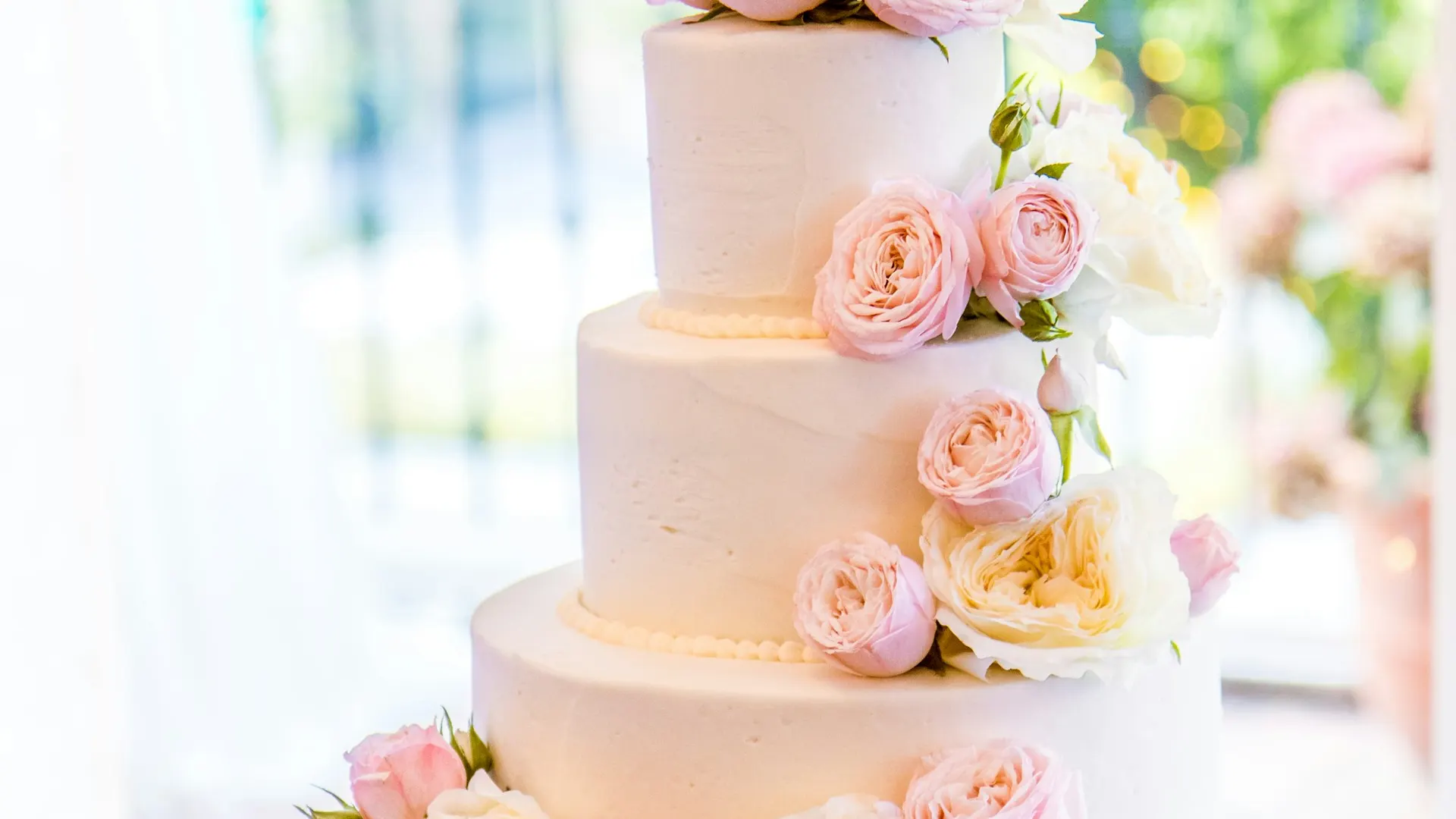 A simple tiered wedding cake with fresh flowers on a wooden table.